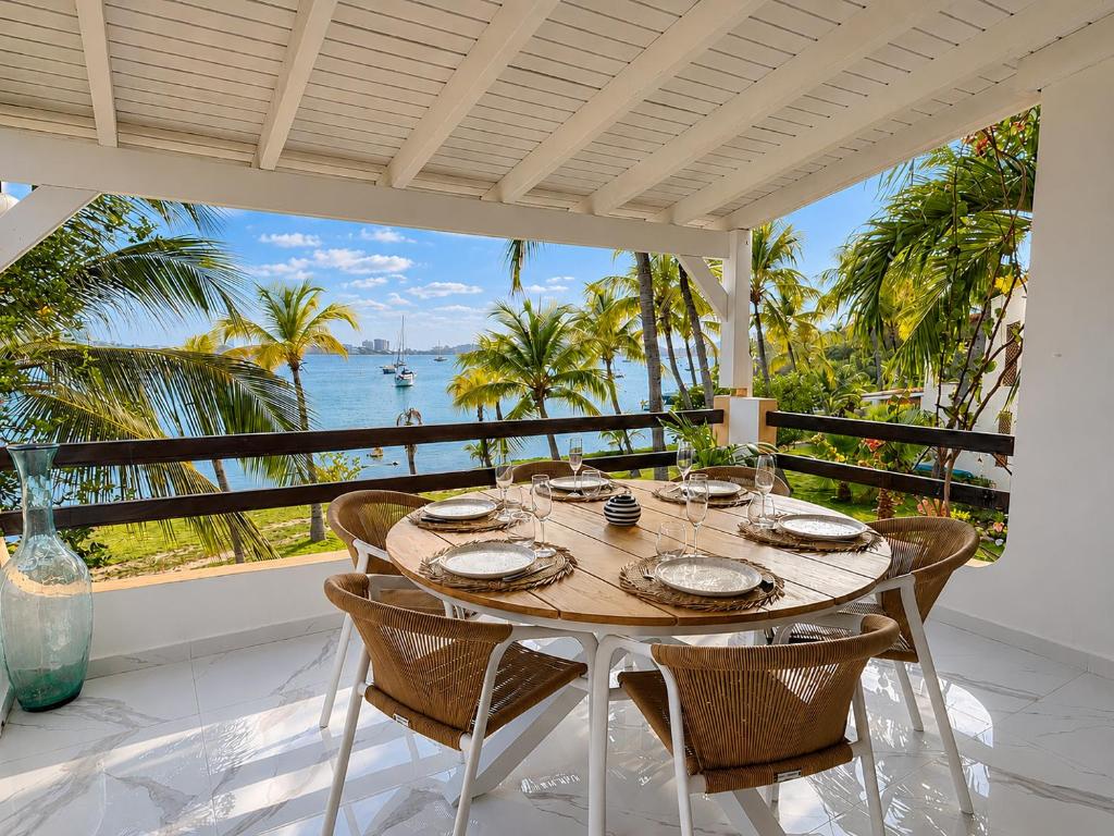 a table with chairs and a view of the ocean at Sunset Paradise in Baie Nettle