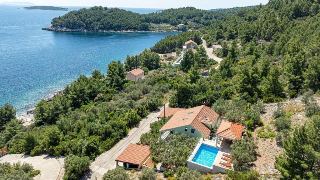an aerial view of a house on a hill next to the water at Apartman Mario with pool by Villas Guide in Blato