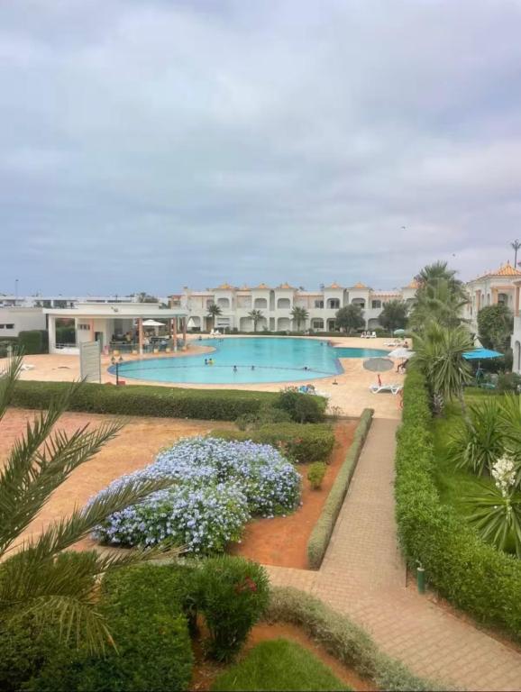 a resort with two swimming pools and flowering plants at Mozona beach 2 in Sidi Rahal