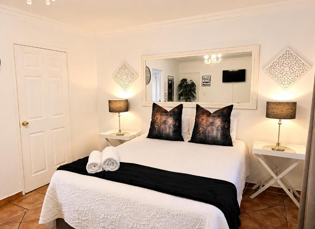 a bedroom with a large white bed with two lamps at Zhantique Guest House 1- Unit 5 in Boksburg