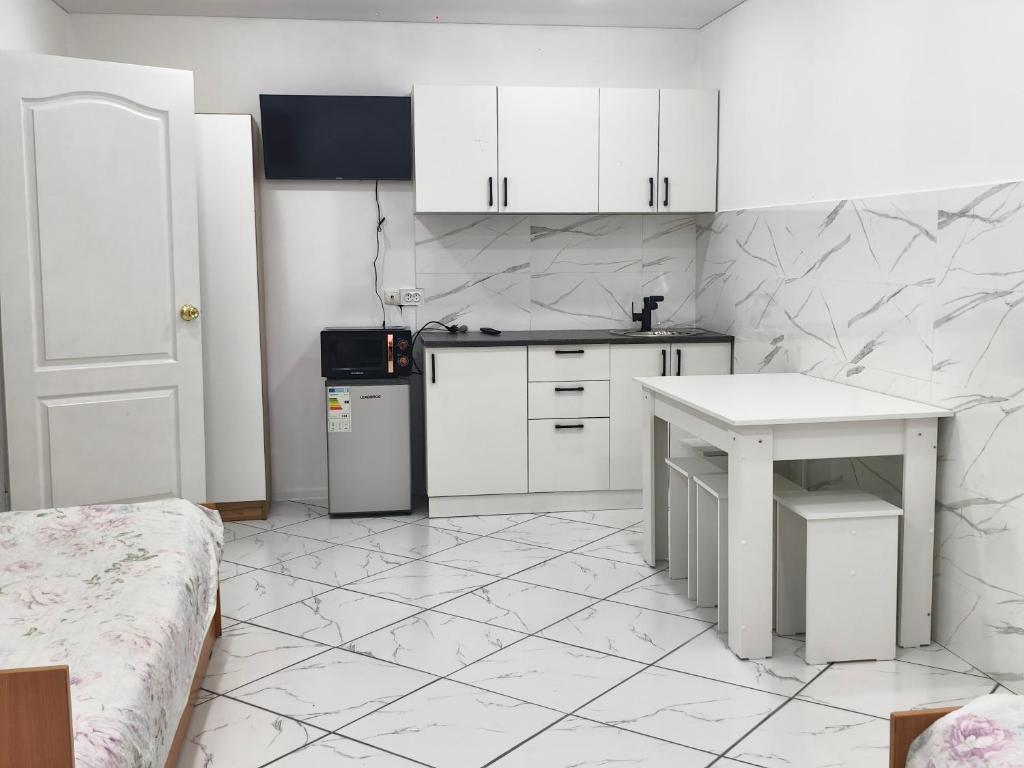 a kitchen with white cabinets and a white table at Rassvet in Lenīnogorsk