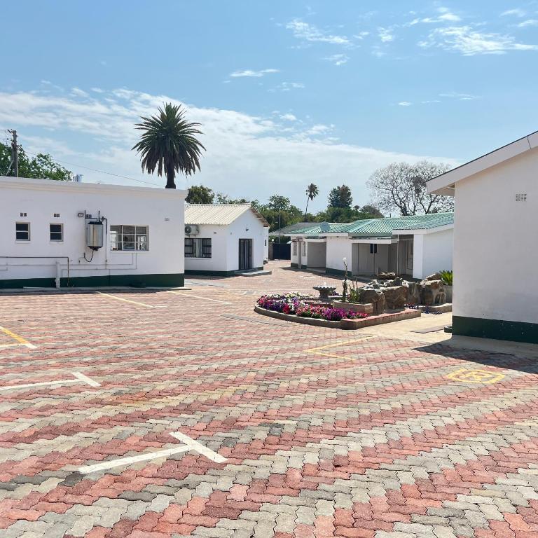 a brick parking lot with a palm tree and buildings at Cumberland Guest Lodge in Bulawayo