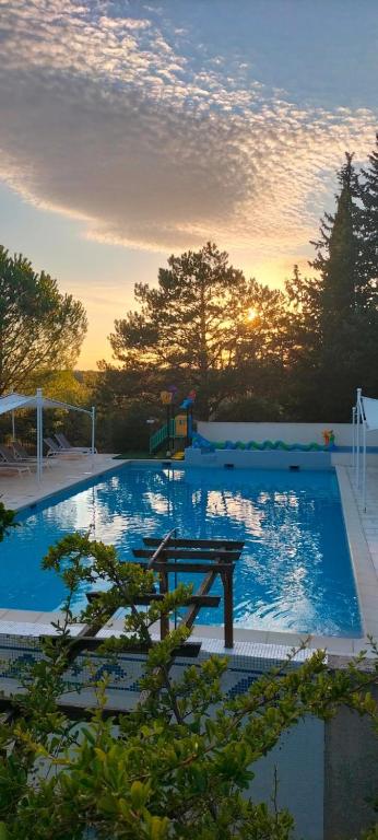 a large swimming pool with a sunset in the background at Camping 3 étoiles - Piscine - ccbfii0 in Châteauneuf-de-Gadagne