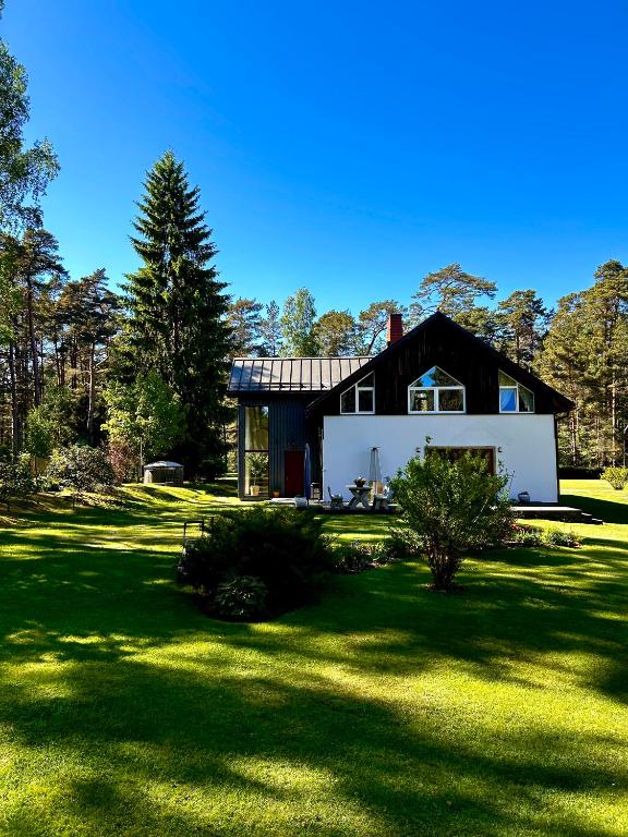 a black and white house on a grass field at Atpūtas vieta Brāļtīrumi in Pūrciems