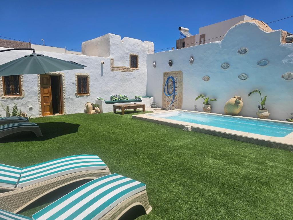 a backyard with a swimming pool and a house at Dar Chauphaly in Houmt Souk