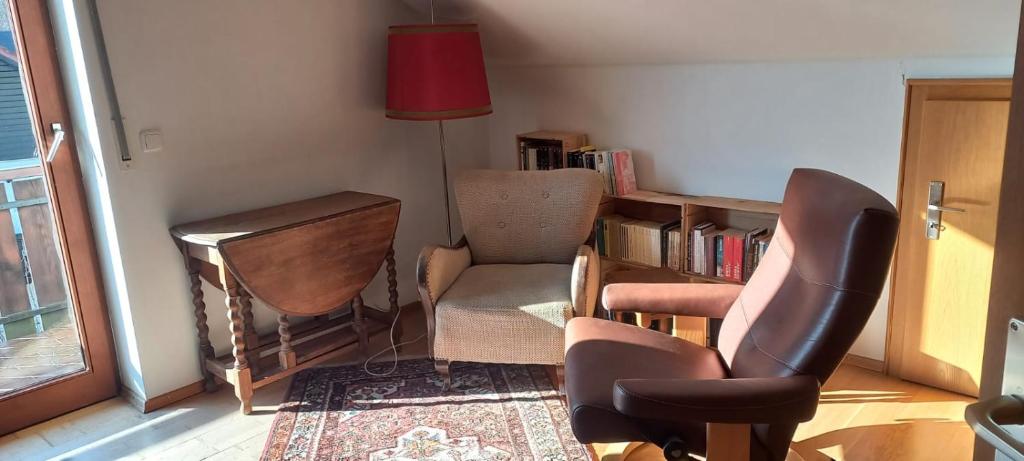 a living room with a chair and a book shelf at Gemütliches Doppelzimmer mit Balkon in Furth im Wald