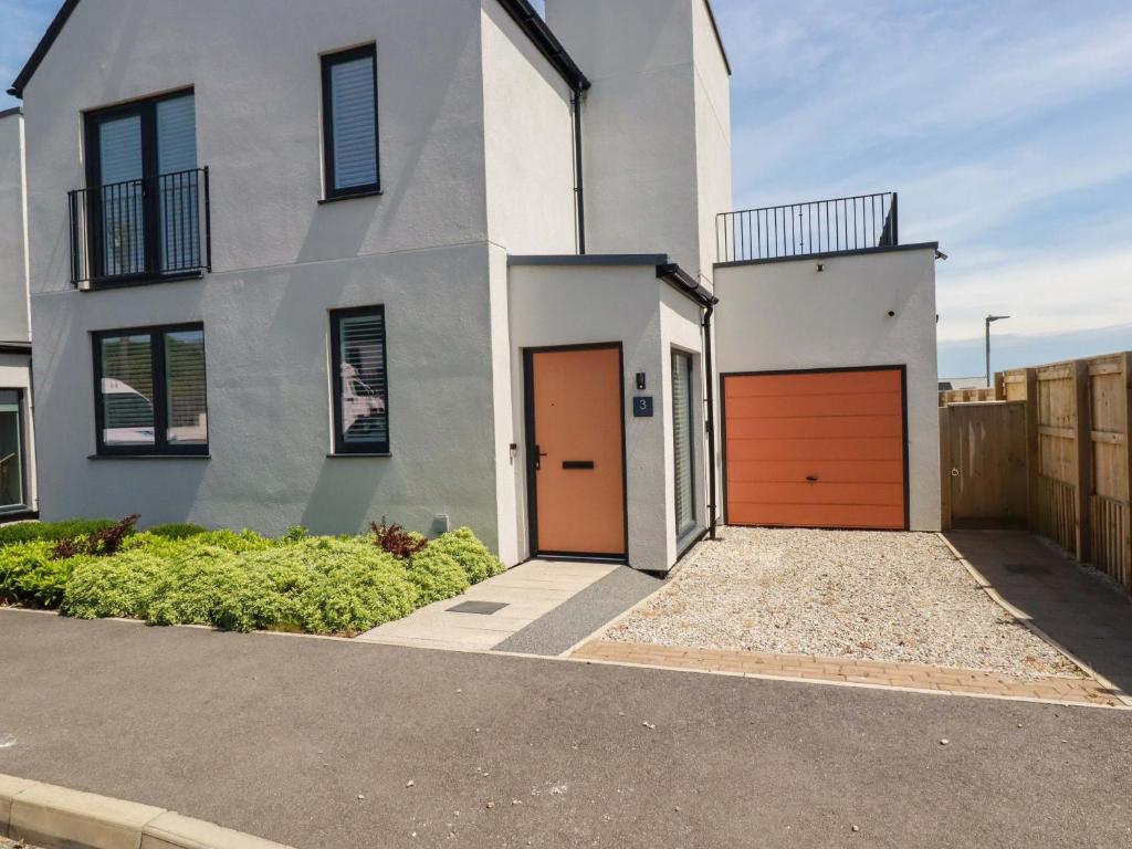 a white house with orange doors and a driveway at Eden's Bloomdale in St Austell