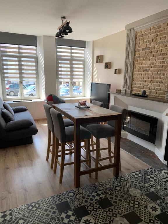 a living room with a table and chairs and a fireplace at Le clocher d Ardres in Ardres