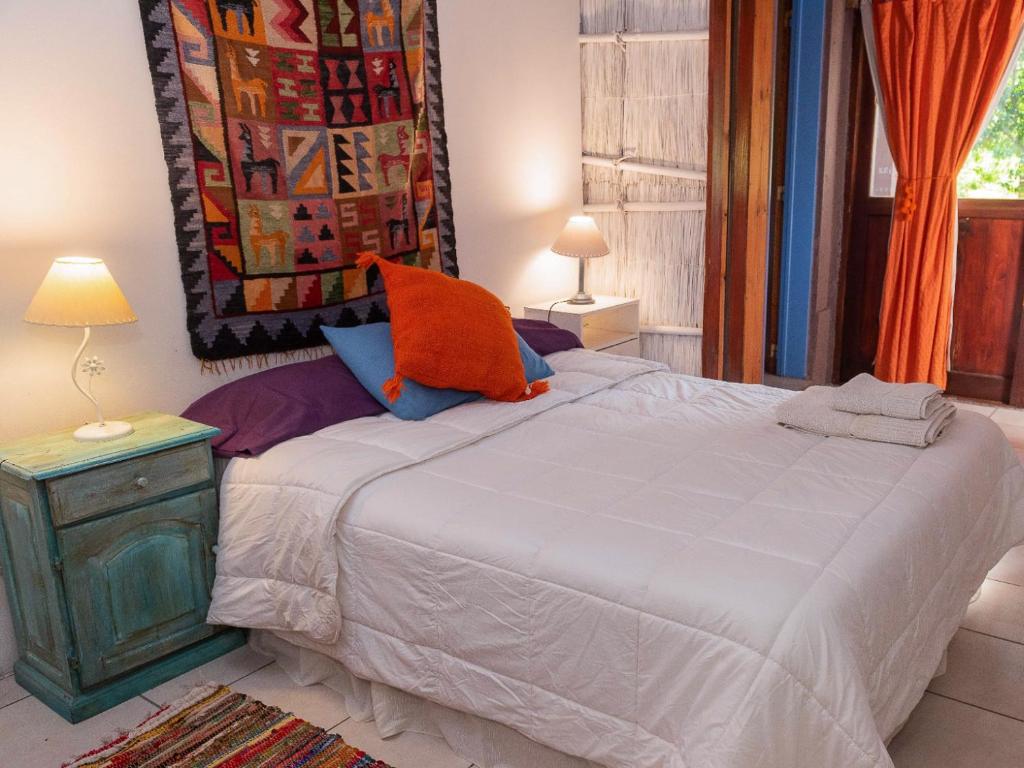 a bedroom with a bed with an orange pillow on it at Gran Cabaña con parque en Catamarca in San Fernando del Valle de Catamarca