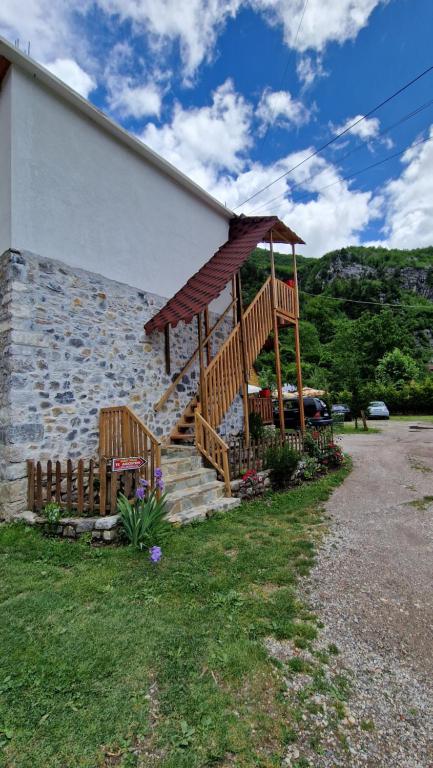 a building with a wooden staircase next to a house at Guest House in Theth Agostini in Theth