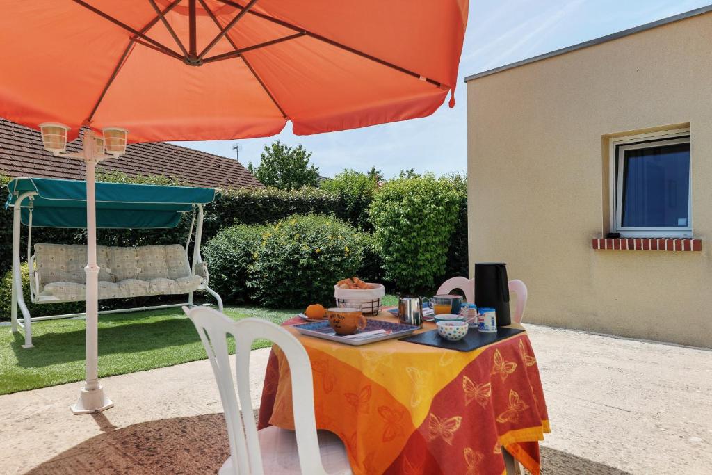 a table with a cake and an orange umbrella at chambre d'hôtes des bleuets in Saint-Firmin-des-Prés