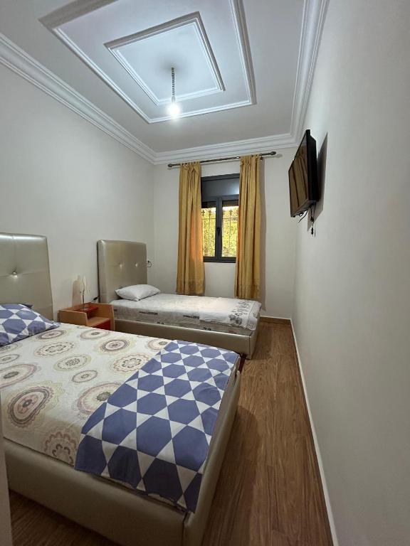 a bedroom with two beds and a tv on the wall at DAR Assoul in Khenifra