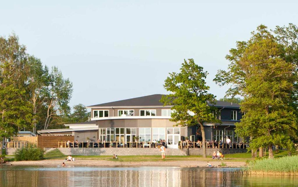 a large house with a lake in front of it at Ringsjöstrand Camping, Hotell och Stugby in Hörby