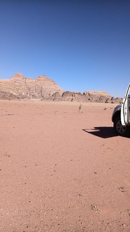 a car parked in the desert with mountains in the background at Star camp luxury in Al Mudawwarah