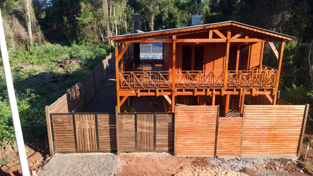 a wooden house with a deck on top of a hill at Encantos del Monte in Gobernador Roca