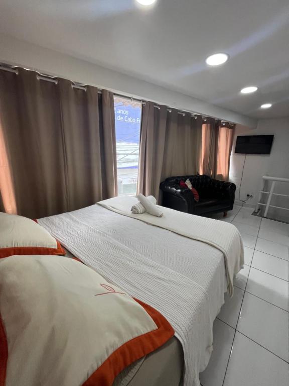 a hotel room with two beds and a window at Loft Aloha in Cabo Frio