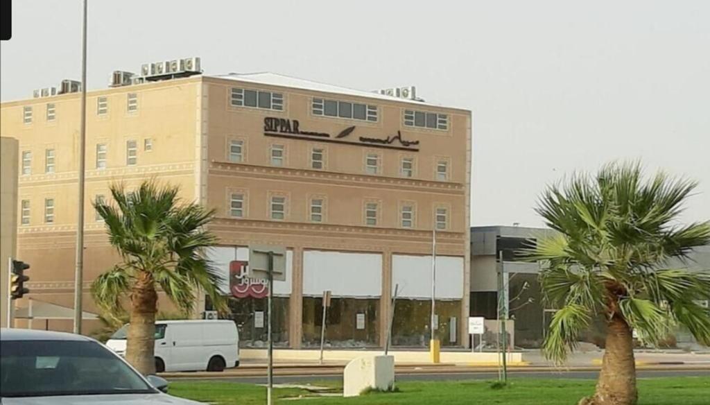 a building with palm trees in front of it at SPAR Serviced Apartments- سيبار للشقق المخدومة in Al Hofuf