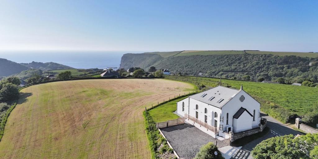 an aerial view of a white house in a field at Brock's Beach House in Saint Gennys