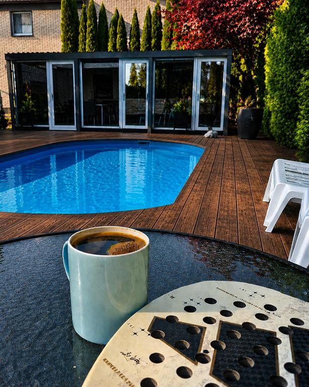 a cup of coffee sitting on a table next to a swimming pool at Pool Hause Palanga in Palanga