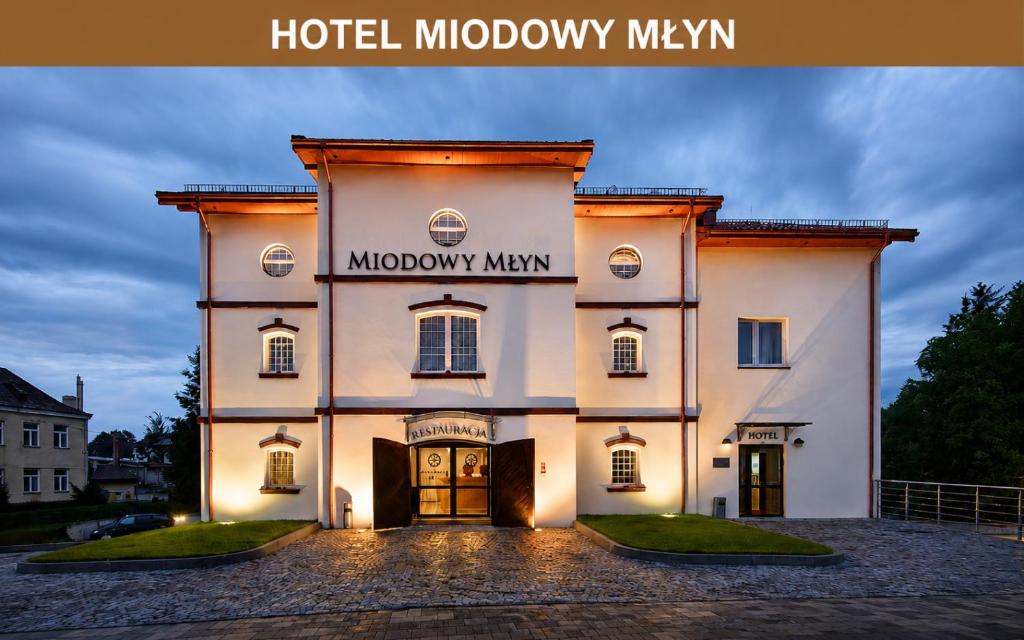 a large white building with a sign on it at Hotel Miodowy Młyn in Opatów