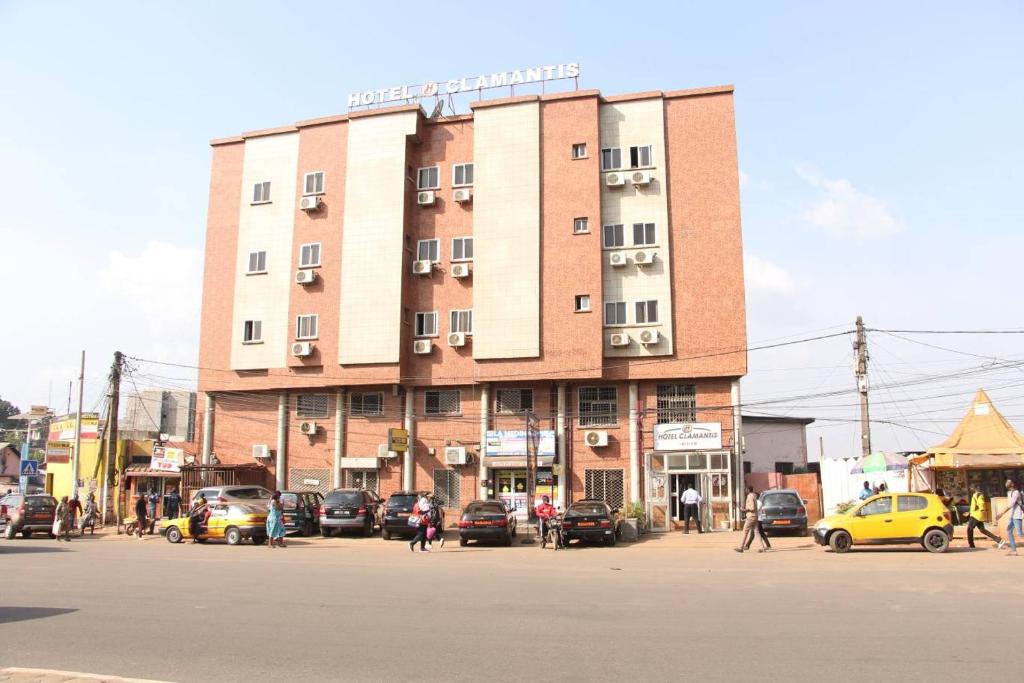 a large building with cars parked in front of it at Hotel Clamantis in Yaoundé