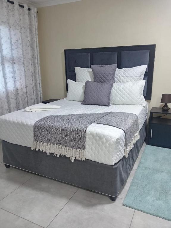 a bedroom with a large bed with white and gray pillows at Sydney's Guest House in Johannesburg