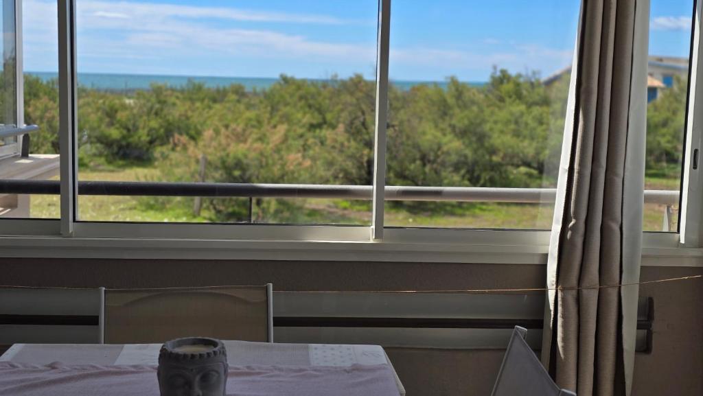 a table and chairs in front of a large window at La Rose des Sables - face à la mer in Frontignan