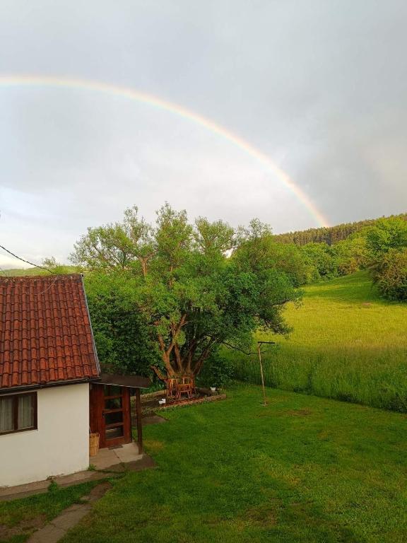 a rainbow in the sky over a house with a yard at Apartment Enjoy in Kolašin