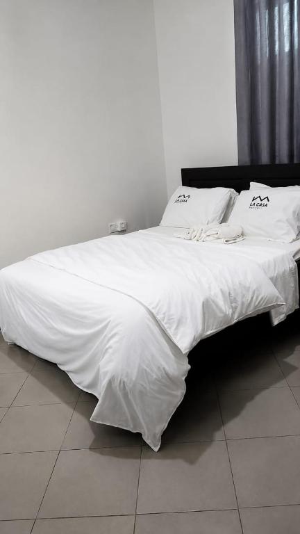 a large white bed with white sheets and pillows at La casa Motel in Kahama