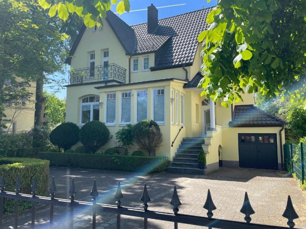 a yellow house with a fence in front of it at Villa Stolle, Ferienwohnung in Schneverdingen