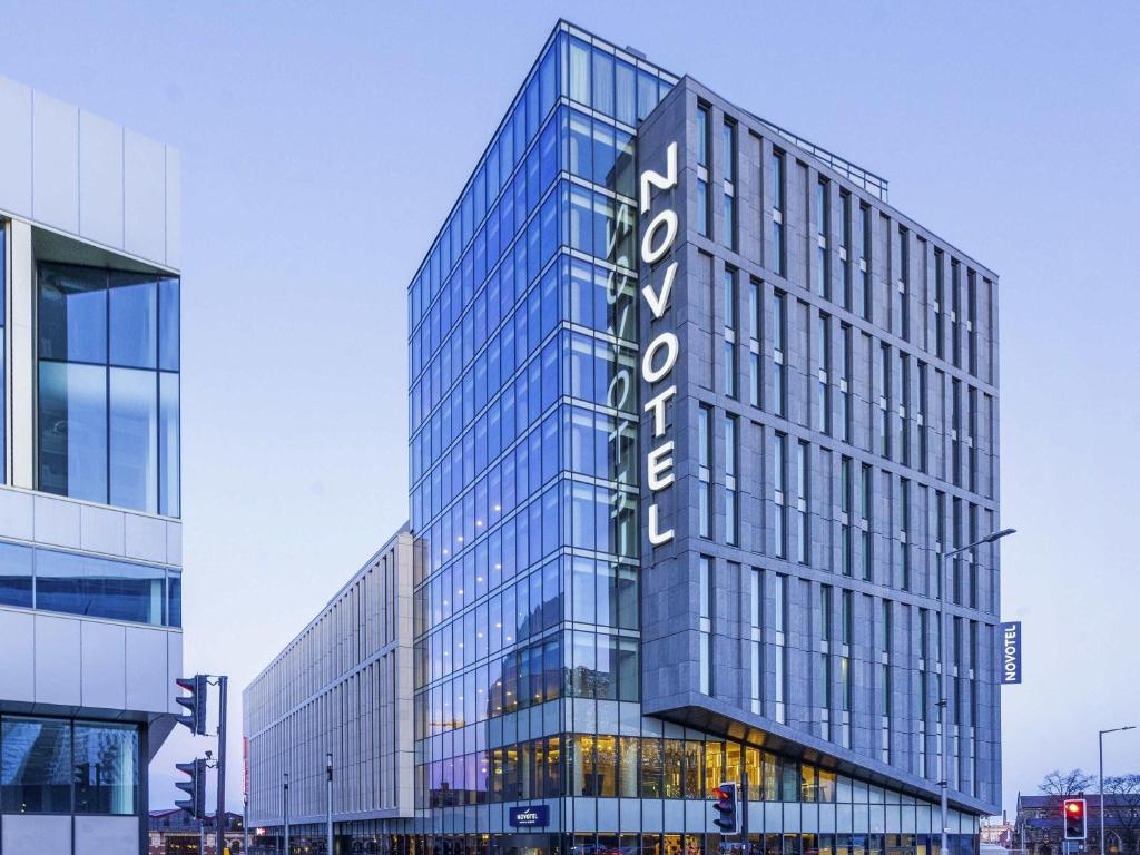 a tall glass building with a sign on it at Novotel Leicester in Leicester