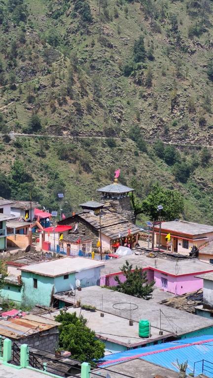 a group of buildings with a mountain in the background at Chaukhamba Pine Cottage & HomeStay in Rānsi