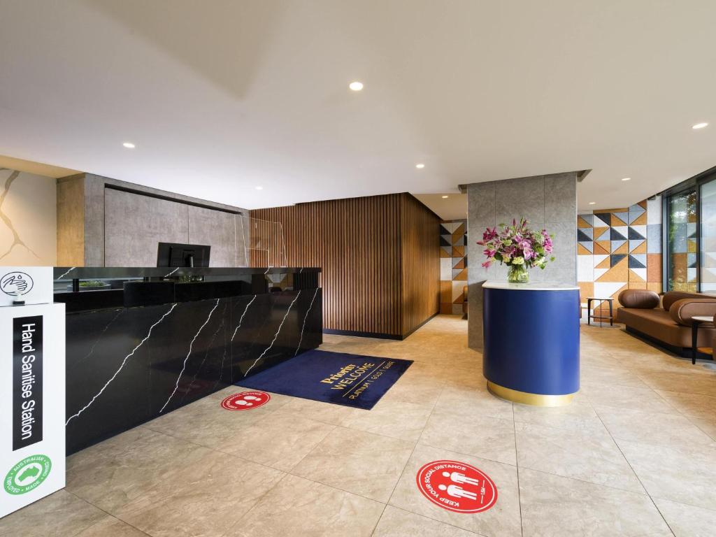 a hotel lobby with a reception desk with flowers on the floor at The Sebel Melbourne Moonee Ponds in Melbourne