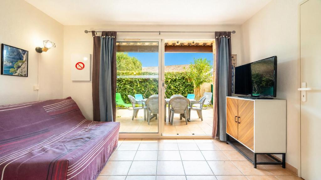 a bedroom with a bed and a television and a patio at Samaria Village N08 - 2P4 in Agde