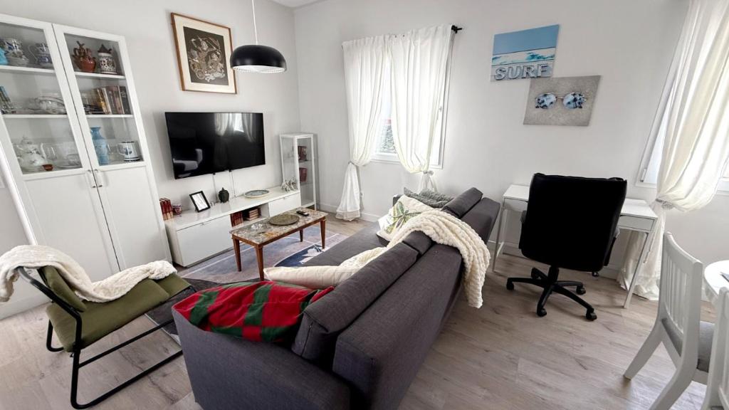 a living room with a gray couch and a desk at Posadas de María Casa María 3 in Talavera de la Reina