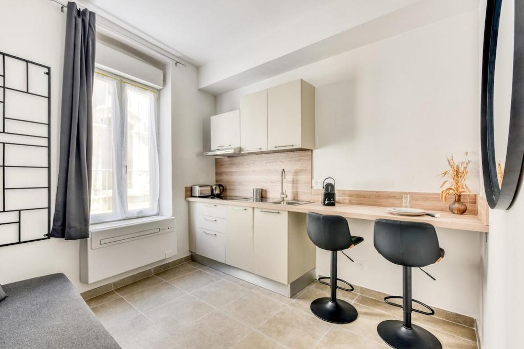 a kitchen with white cabinets and two chairs in it at La Petite Maison - Studio in Peyriac-de-Mer