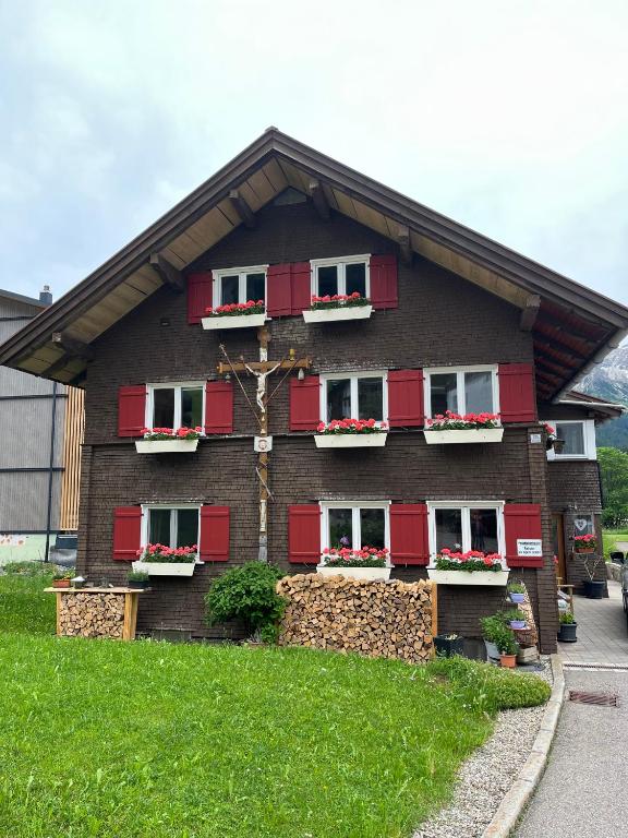 a house with red shuttered windows and a tree at Alpenheimat 1658 in Mittelberg