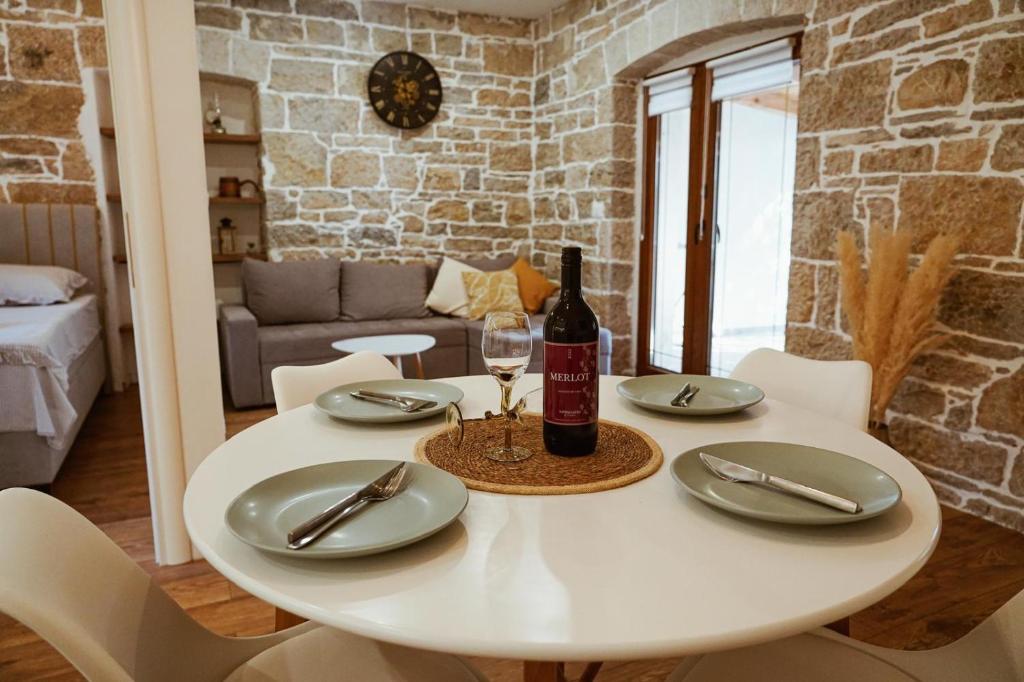 a white table with a bottle of wine and a glass at Nada Apartment near Krka National Park in Skradin