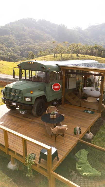a green bus parked on a wooden deck at D'Alma Bus com café da manhã in Pomerode