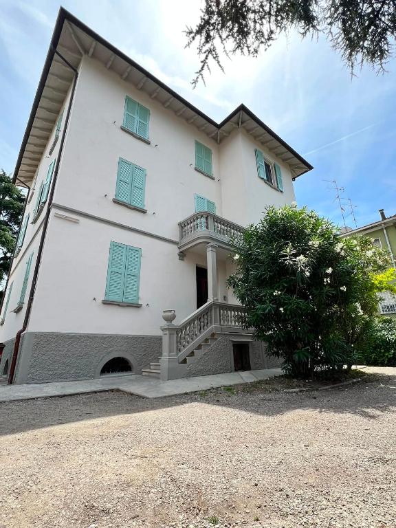 a large white building with blue shuttered windows at Urban Apartments RE in Reggio Emilia