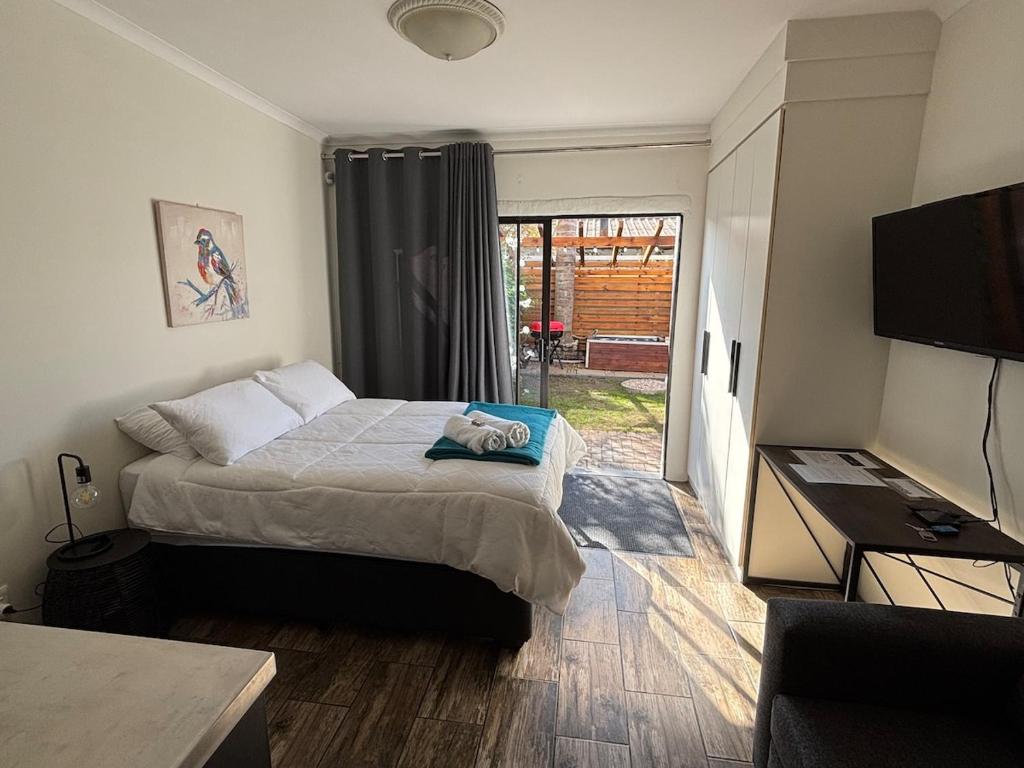 a bedroom with a bed and a flat screen tv at Urban Nest Self Catering in George