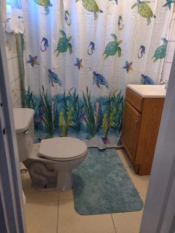 a bathroom with a toilet and a shower curtain with fish at casa Verano in Cabarete