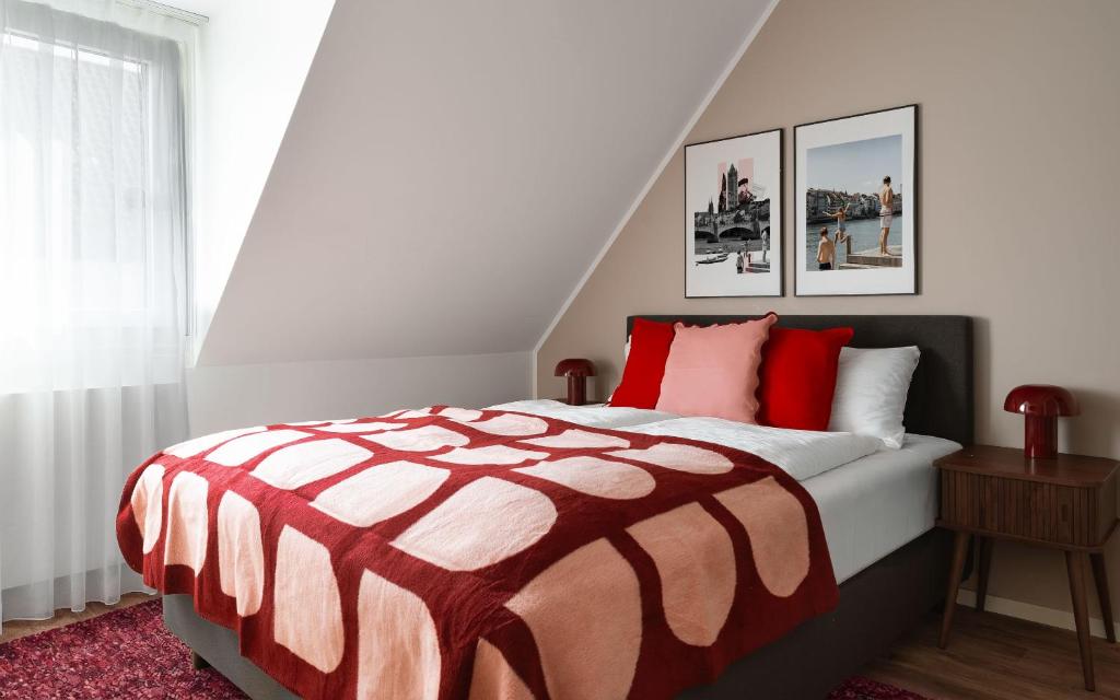 a bedroom with a bed with a red and white comforter at Limehome Basel Town Hall in Basel