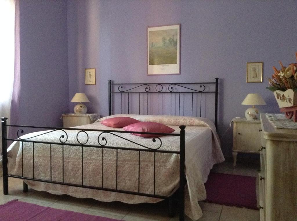 1 dormitorio con 1 cama con almohadas rosas en I 99 ulivi, en Cavour