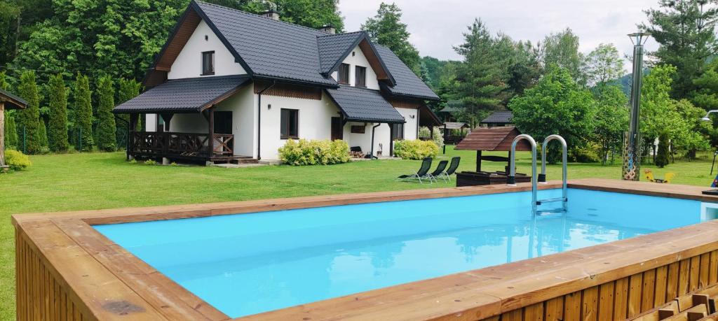 a large swimming pool in front of a house at Chaty Gajowego w Bieszczadach z basenem 517-665-624 in Bukowiec