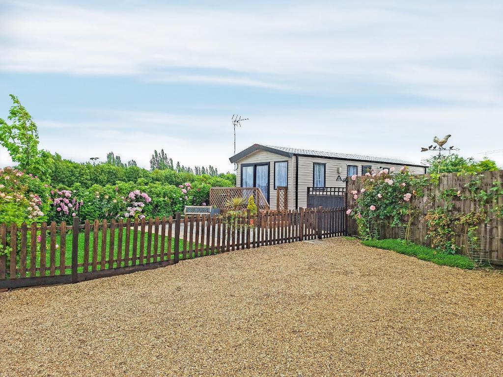 a fence in front of a house at Windy Roost Lodge in Tydd Saint Giles