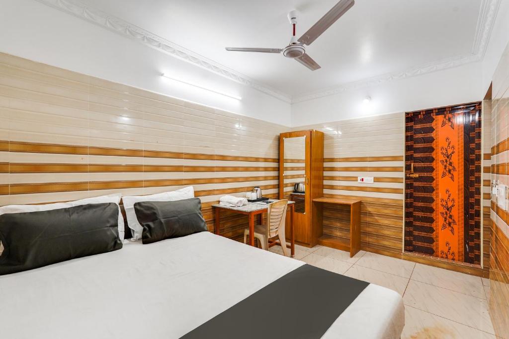 a bedroom with a bed and a desk in it at Hotel O Sharmila Guest House in Pondicherry