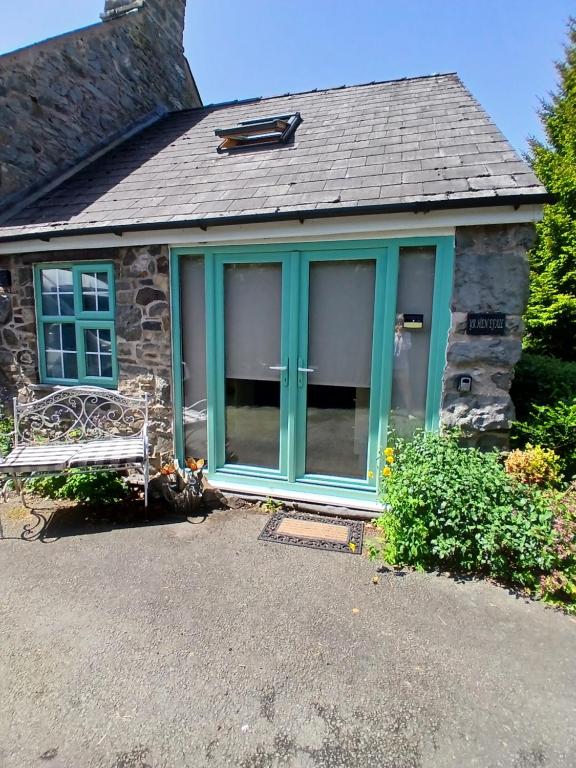 a front door of a stone house with blue doors at Yr Hen Efail - Quirky Old Smithy cottage near forest walks, cycling & lakes in Garthbeibio