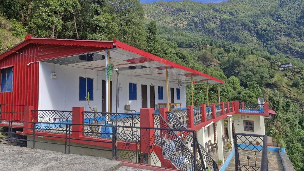a red and white building with a balcony on a hill at The Captain's Quarters in Ukhimath