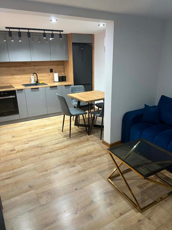 a living room with a table and a blue couch at LUX HOUSE Roztocze Sauna i Bania z hydromasażem in Krasnobród